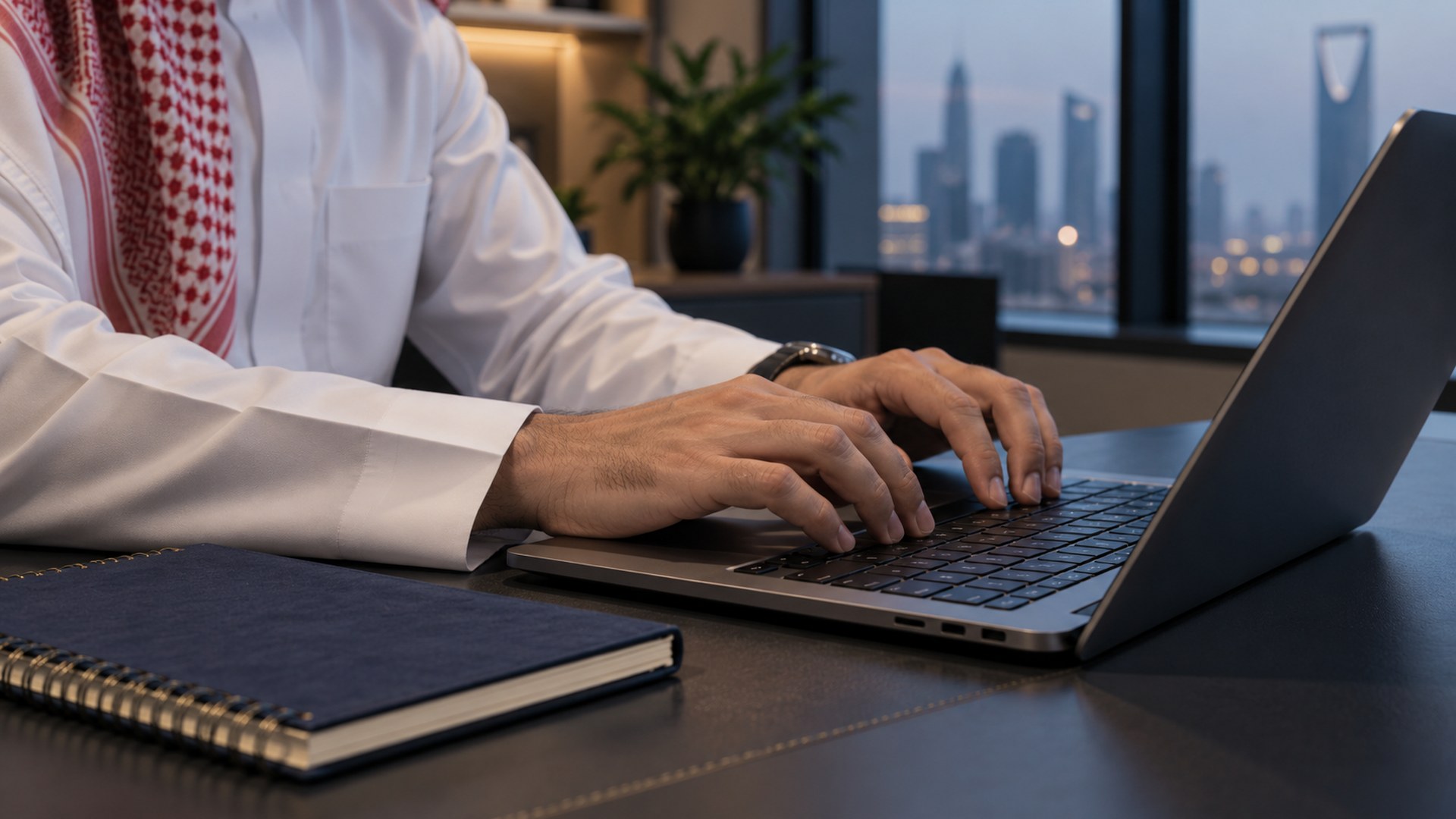 يدان تكتبان عبارات بحث محددة على لابتوب في مكتب سعودي حديث