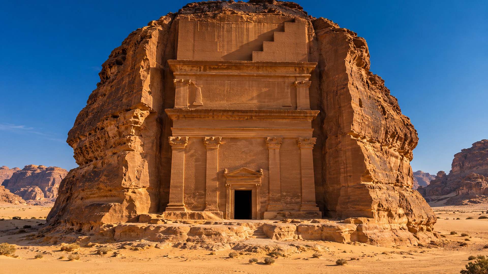 واجهة مقبرة نبطية ضخمة منحوتة في الصخر بالحِجر في العلا وحولها رمال ذهبية