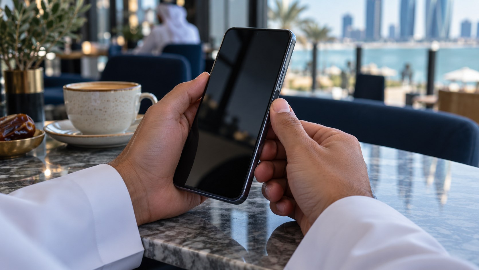 شخص يفتح جواله ببصمة الإصبع على طاولة مقهى