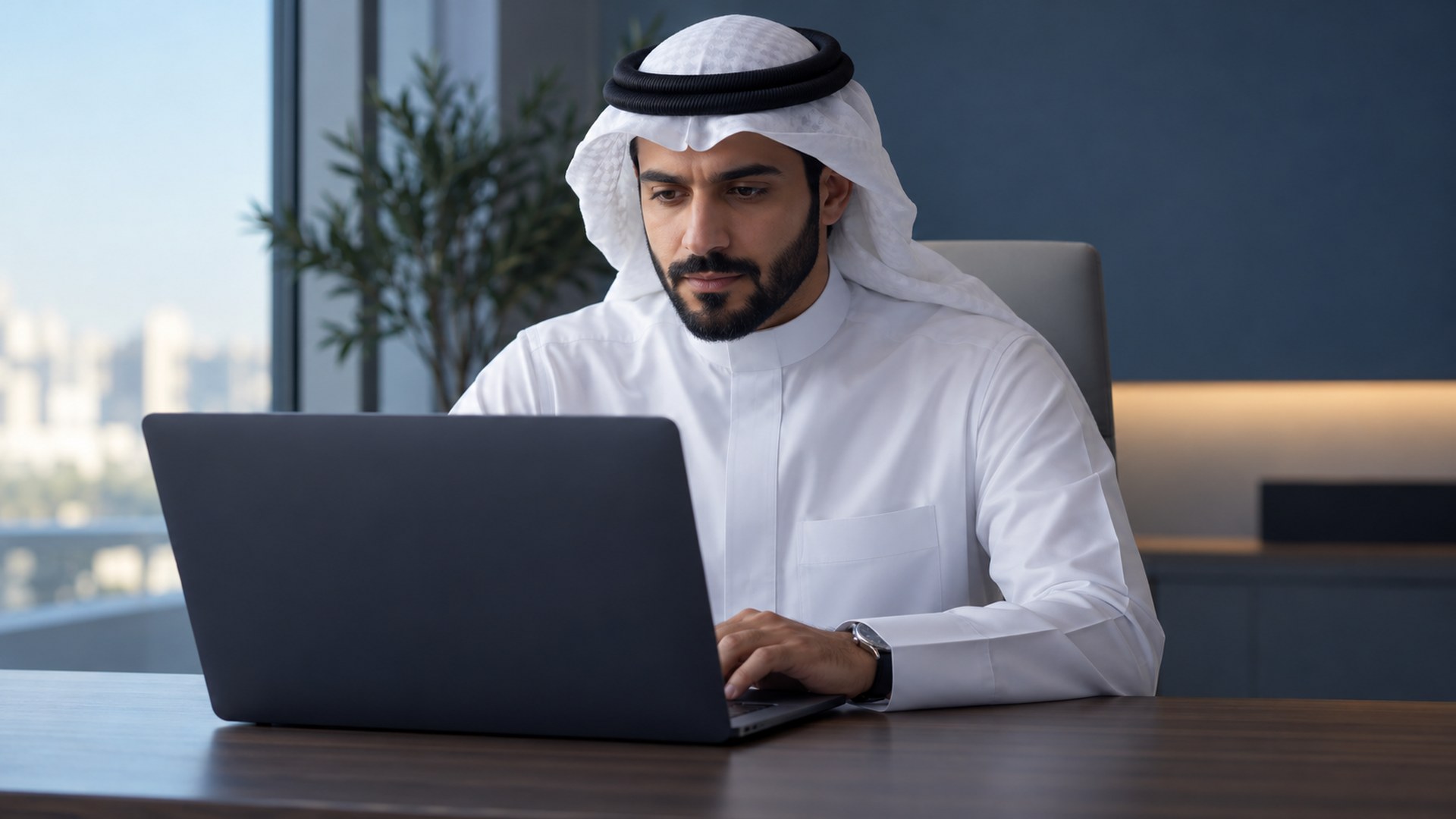 صانع محتوى سعودي يتفقد مهمة عملية على اللابتوب في مكتب بسيط