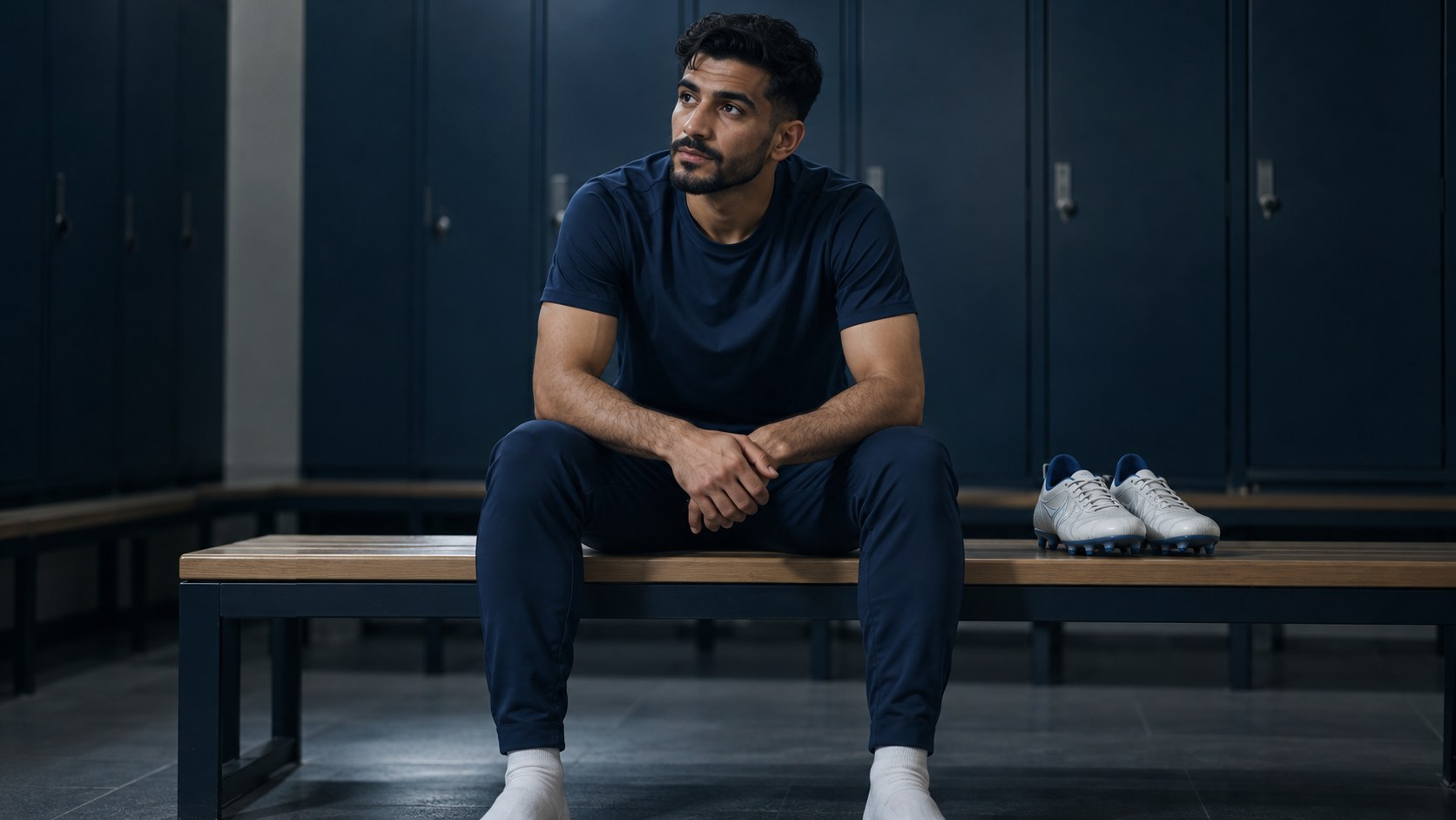 لاعب كرة قدم سعودي يرتاح على مقعد بجانب حذائه في غرفة ملابس هادئة