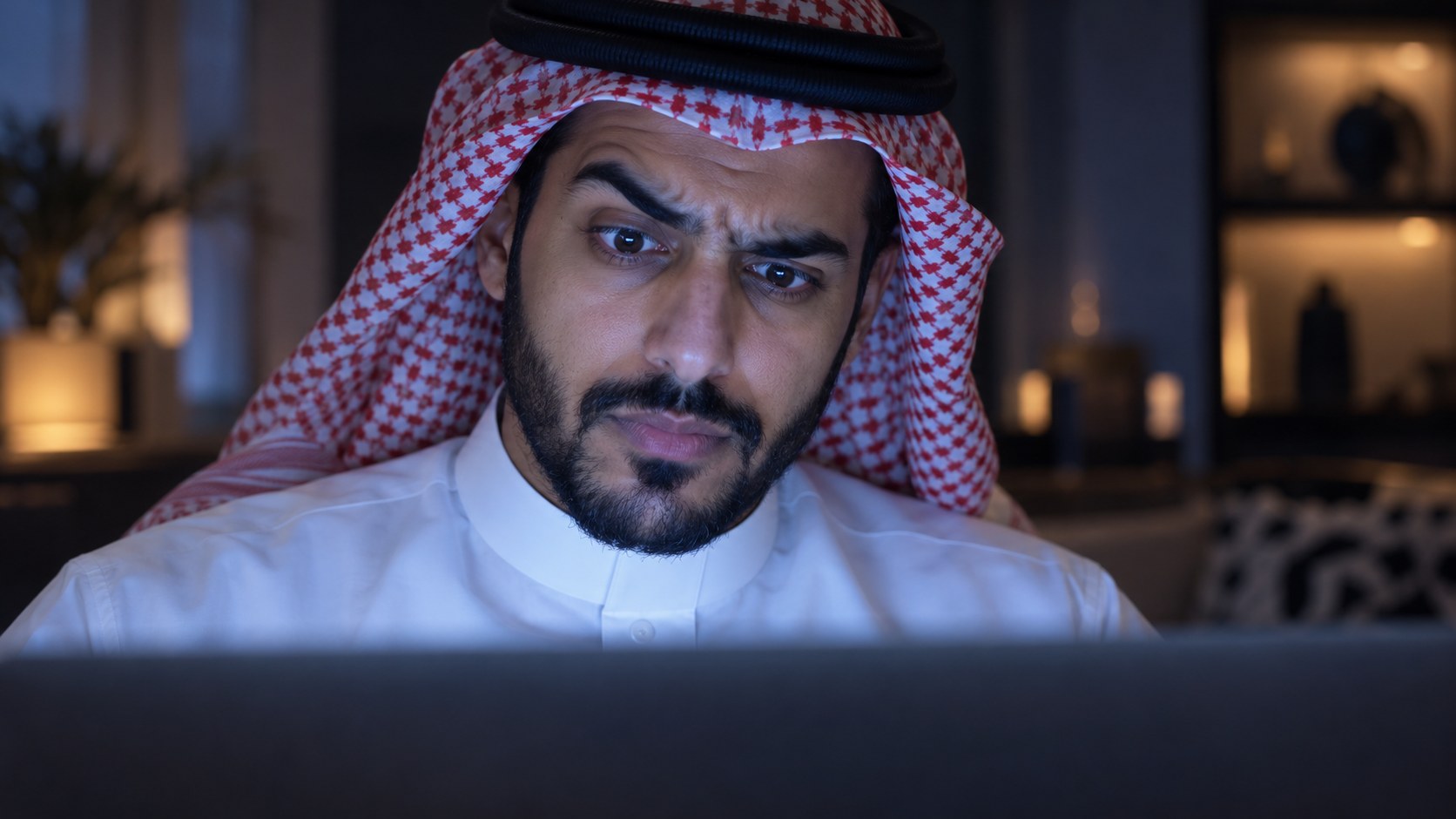 وجه رجل سعودي يضيئه اللابتوب وأمامه عداد مشاهدات كبير وهو يرفع حاجبيه شاكاً
