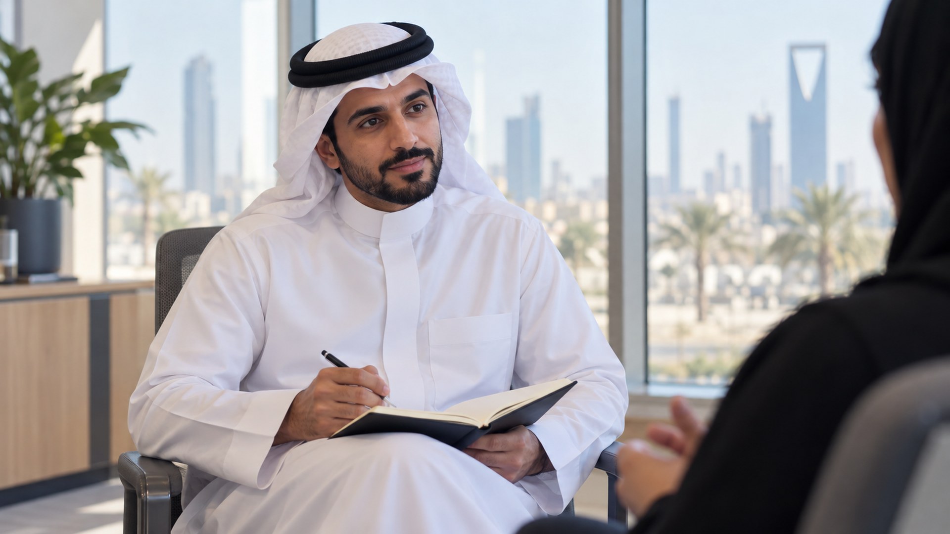 مصمم منتجات سعودي يستمع لمستخدم في مقابلة بحثية بمكتب مضيء