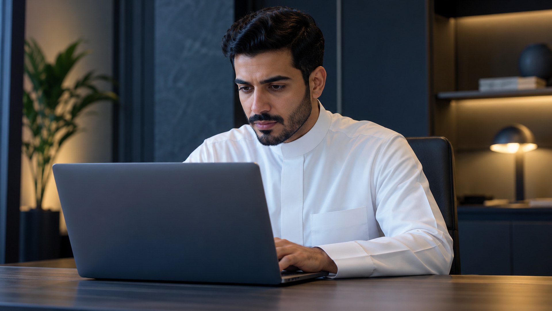 موظف سعودي يختبر موقعاً على اللابتوب بتركيز