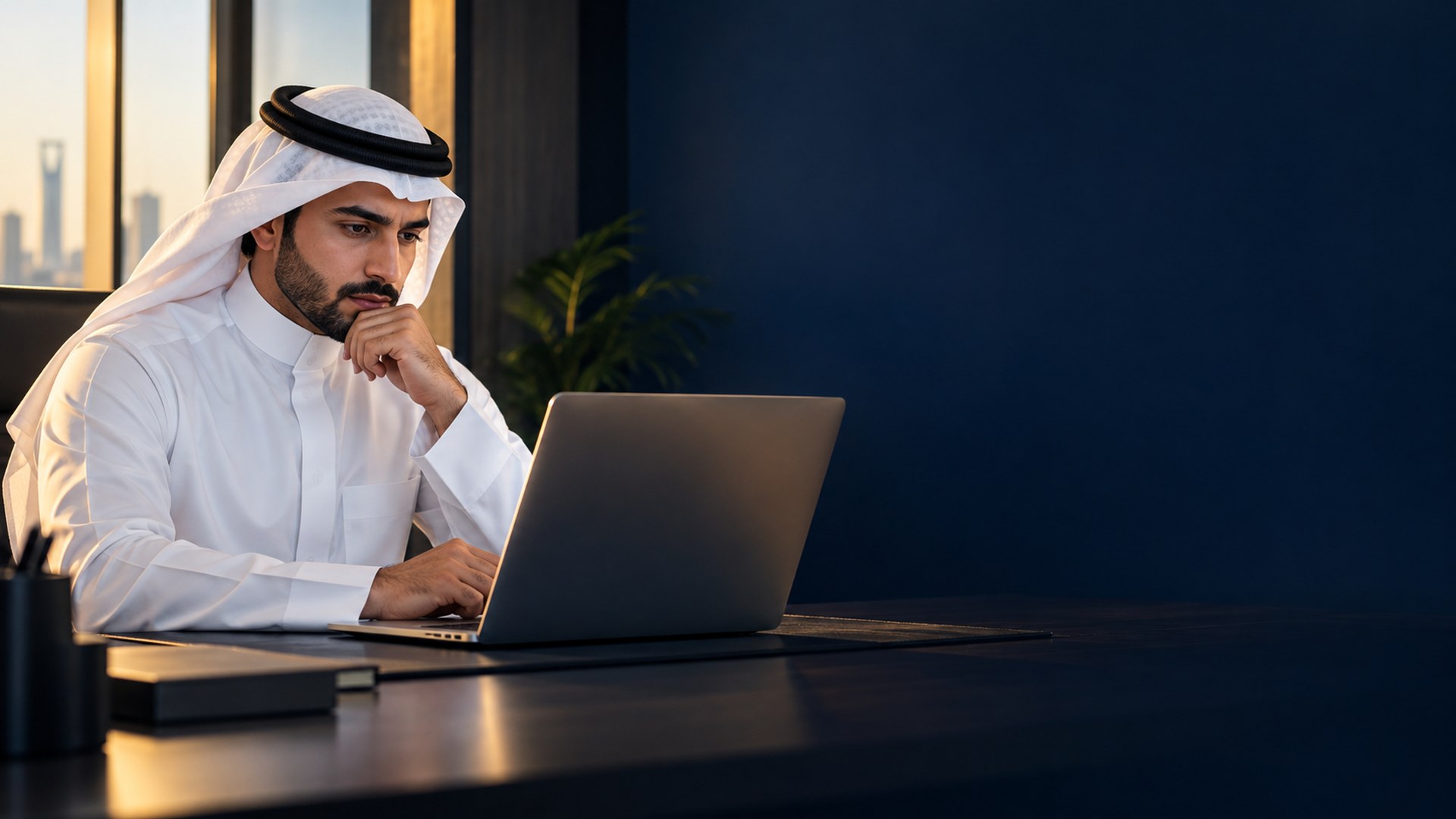 صاحب عمل سعودي شاب بثوب أبيض يتأمل نتائج البحث على شاشة لابتوبه