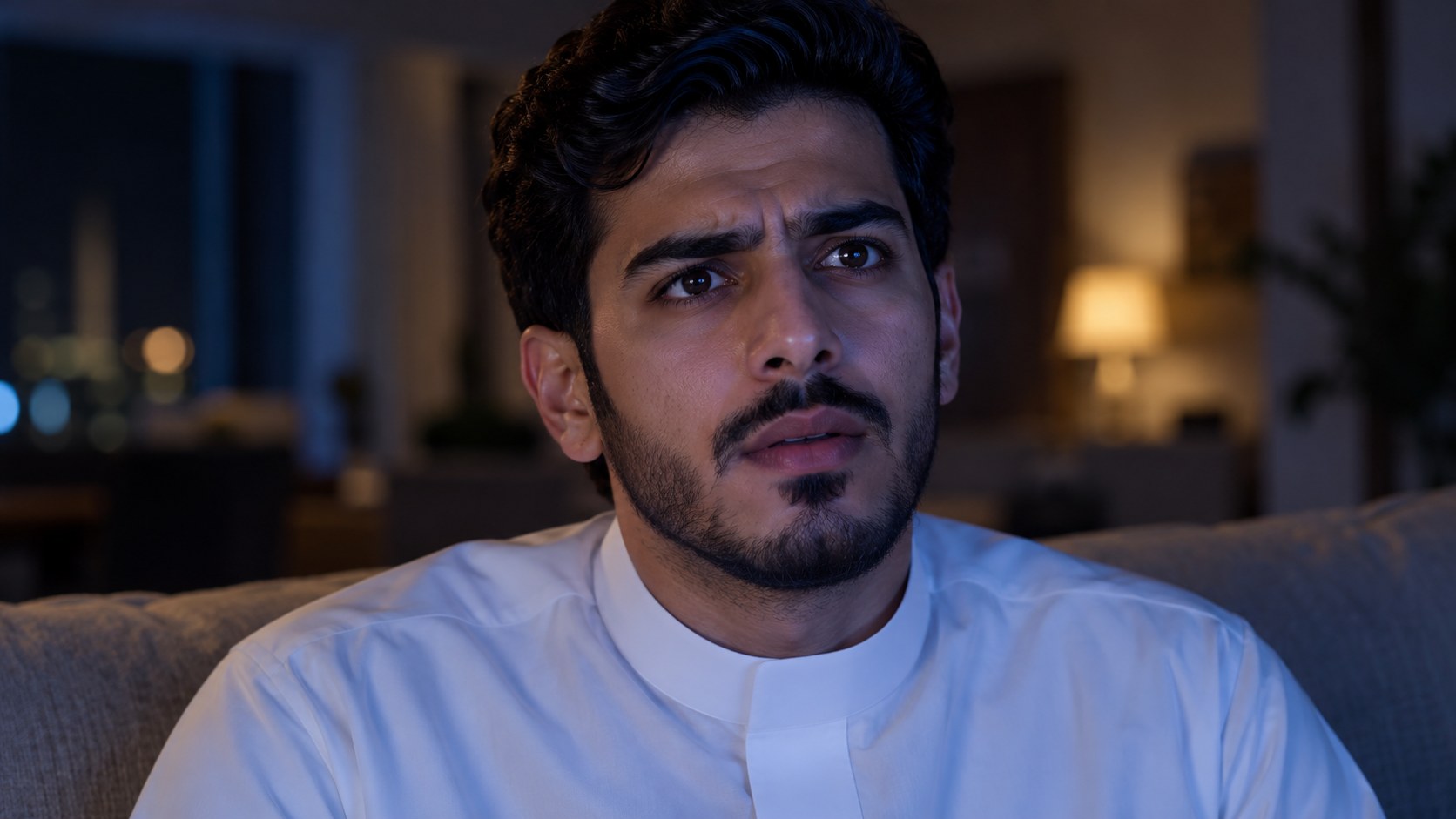 وجه شاب سعودي محتار يضيئه التلفزيون ليلاً