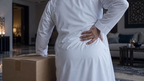 صندوق ثقيل على الأرض ويد رجل تضغط على أسفل ظهره