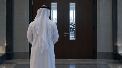 شخص ينتظر أمام باب قاعة اختبار مقفل، من الخلف