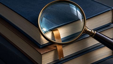 عدسة مكبرة فوق كتب مراجع يبرز منها فاصل