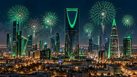 أفق الرياض مضاء بالأخضر ليلاً والألعاب النارية فوقه