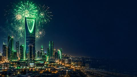 أفق الرياض مضاء بالأخضر ليلاً والألعاب النارية فوق برج المملكة