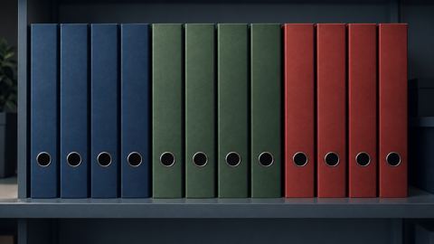صف ملفات مكتبية بثلاثة ألوان على رف، كل لون لقسم