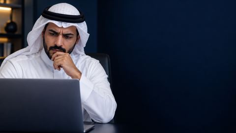صاحب عمل سعودي محتار أمام اللابتوب في مكتب بسيط