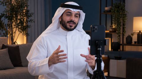 صانع محتوى سعودي يصوّر فيديو قصيراً بجوال على حامل في استوديو منزلي