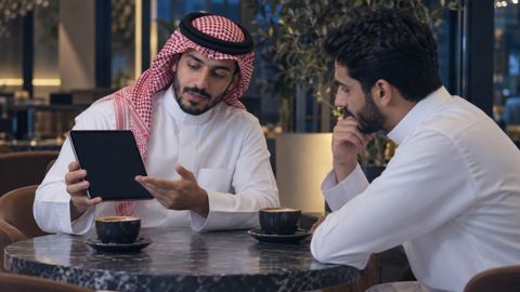 مبتكر سعودي يعرض نموذجاً رقمياً أولياً على مستخدم مهتم في مقهى