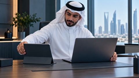 موظف سعودي يجهز لابتوب وجهازاً لوحياً جديدين على مكتب نظيف