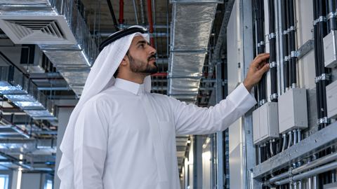 مهندس سعودي يفحص تمديدات كهرباء وتهوية مرتبة داخل مبنى تجاري
