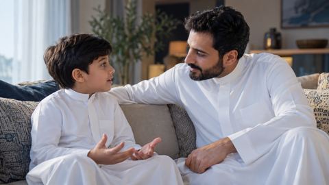 أب سعودي يستمع لطفله الصغير باهتمام في حديث هادئ بالبيت