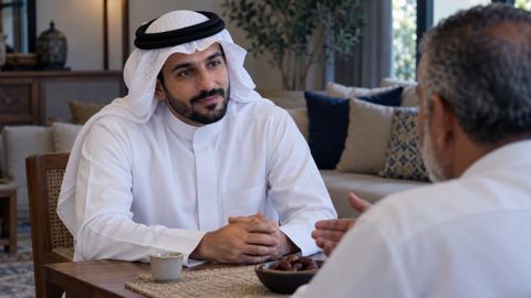 رجل سعودي يستمع باهتمام لأحد أفراد عائلته على طاولة صغيرة في بيت هادئ