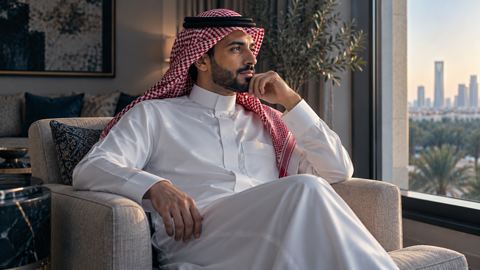 رجل سعودي جالس متأملاً بجانب نافذة صالة مشمسة
