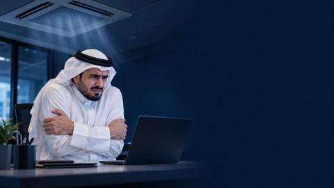 موظف سعودي بالثوب منزعج على مكتبه تحت فتحة تكييف في السقف
