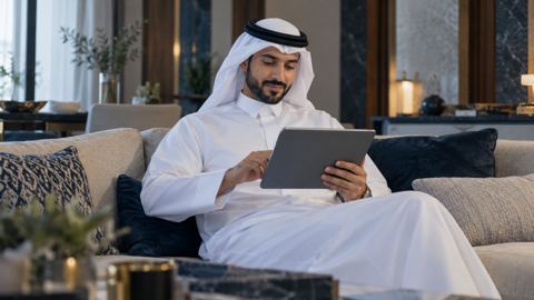 متسوق سعودي على الكنب يتصفح منتجات مقترحة على جهاز لوحي
