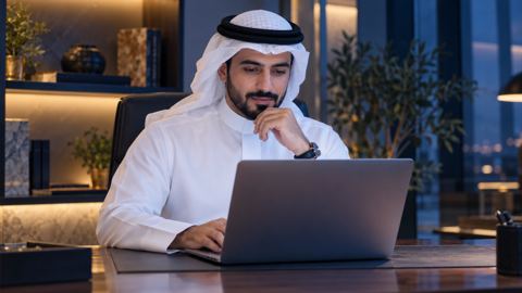 صاحب محل سعودي يراجع موقعه الإلكتروني على اللابتوب
