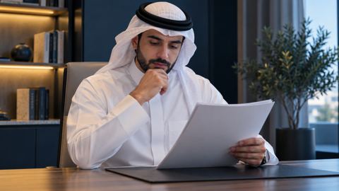 كاتب سعودي يراجع مستنداً مختصراً على مكتب مرتب