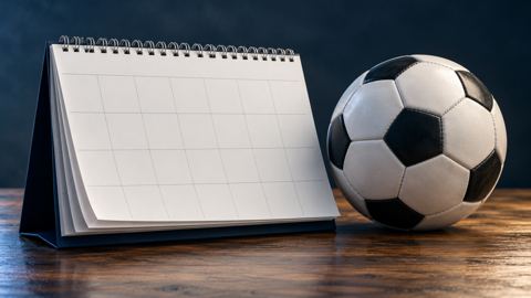 تقويم مكتبي أنيق بجانب كرة قدم رسمية على طاولة خشبية